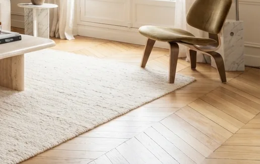 Lounge chair and oak herringbone floor beside a tall window