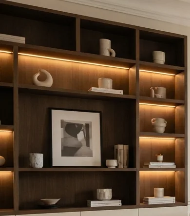 Built-in timber shelving with warm integrated lighting in a renovated apartment